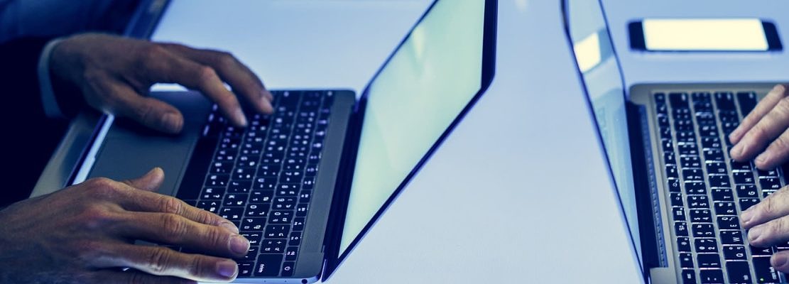 Hand on a laptop working at cyber space table
