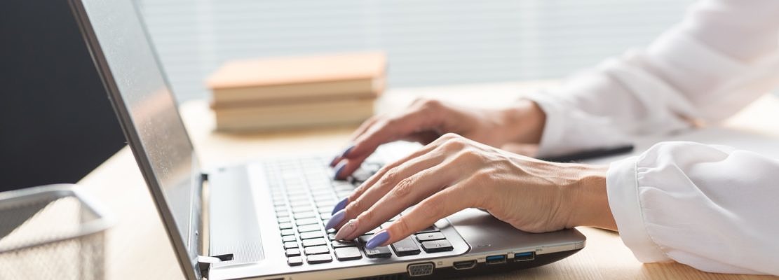 Business, technology and people concept - close up of woman's hands typing in laptop