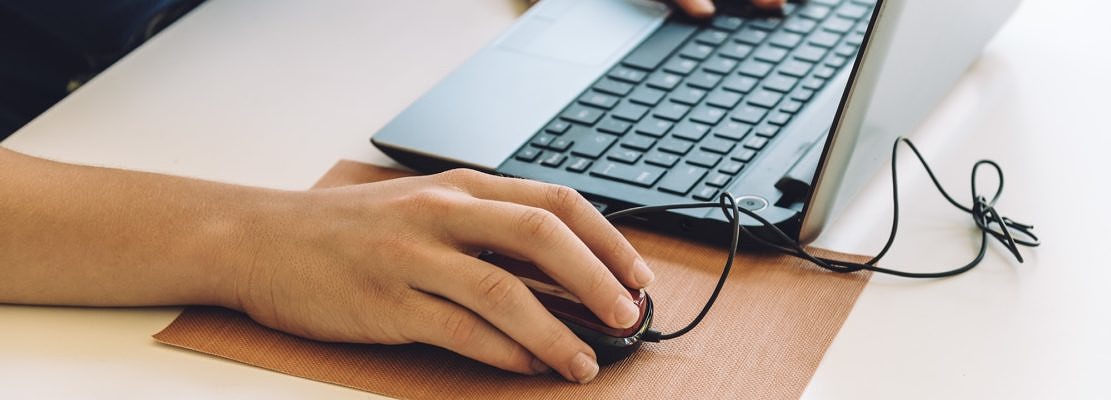 Young man working with laptop, hands on notebook computer and mouse