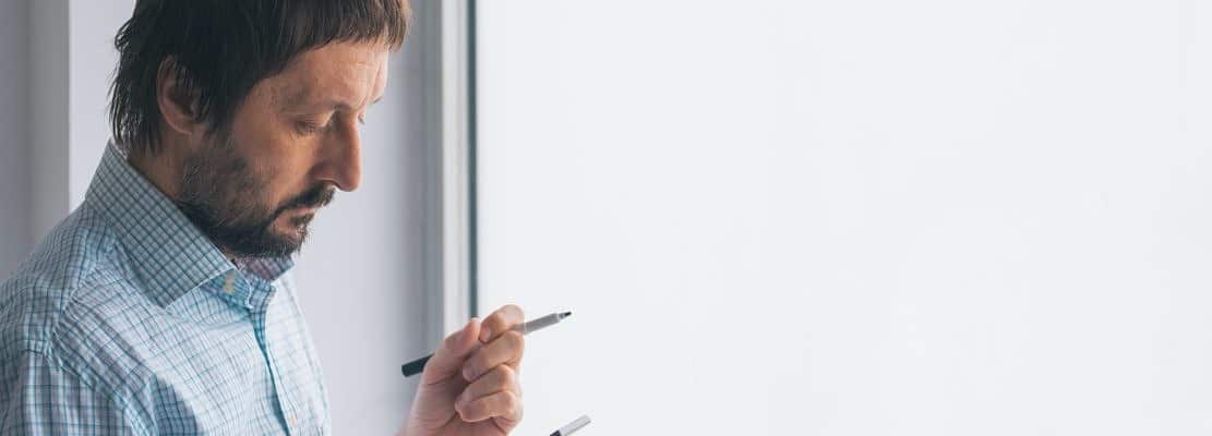 Businessman in office writing on whiteboard