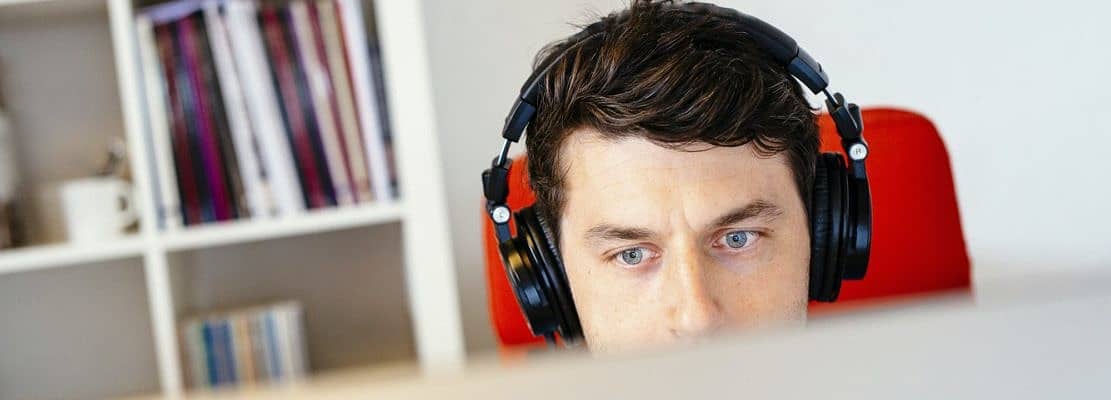 Businessman wearing headphones while using computer in office