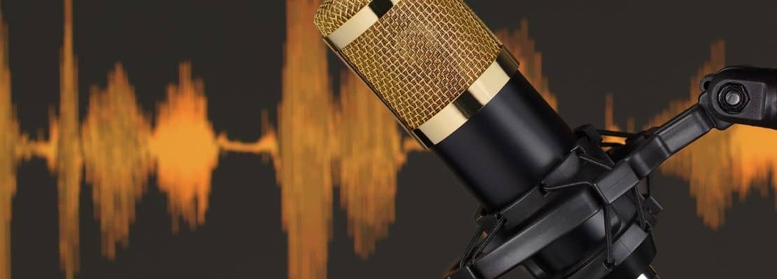 Gold colored condenser microphone over waveform.