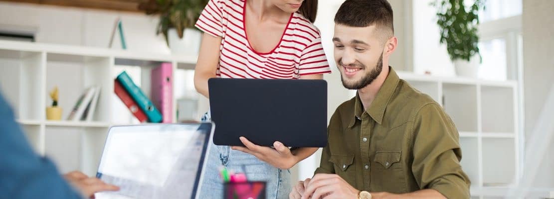 Young smiling business man and woman with laptop working togethe