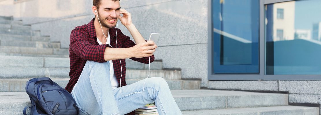 Student sitting on stairs and using smartphone