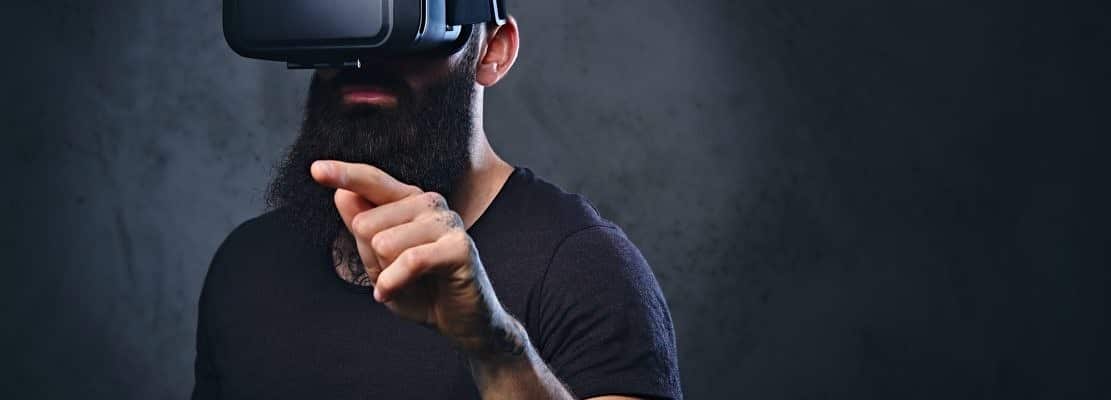 A man with tattoos on arms wearing VR glasses.