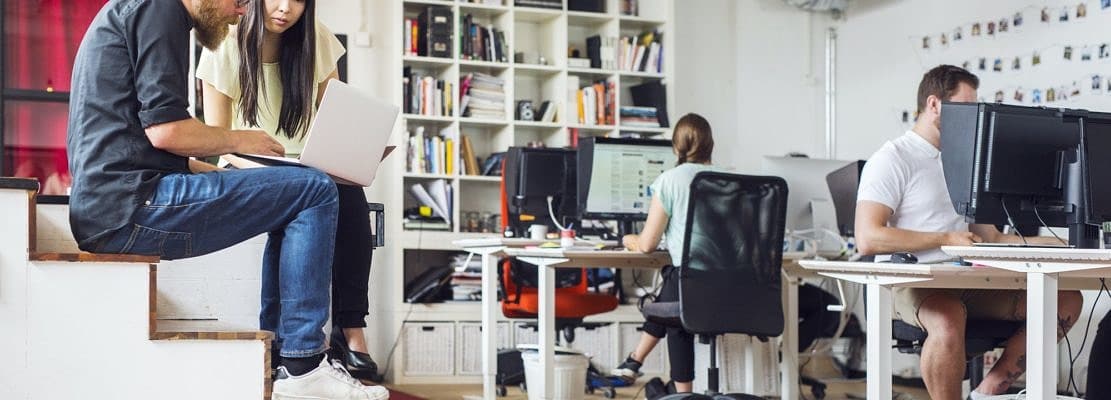 Coworkers using computers at office
