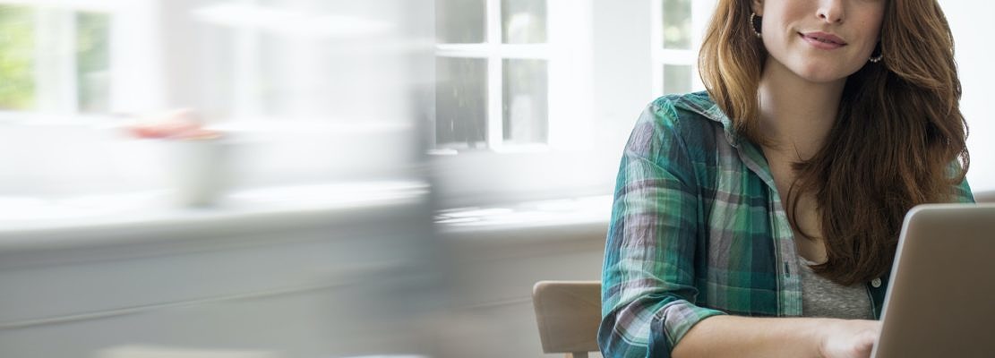 Smiling woman with laptop in home office.