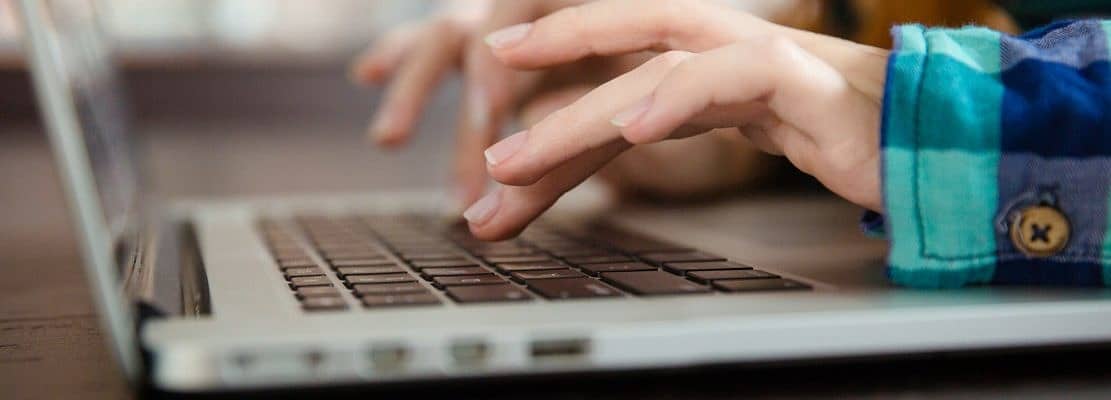 Hands of young woman typing using laptop