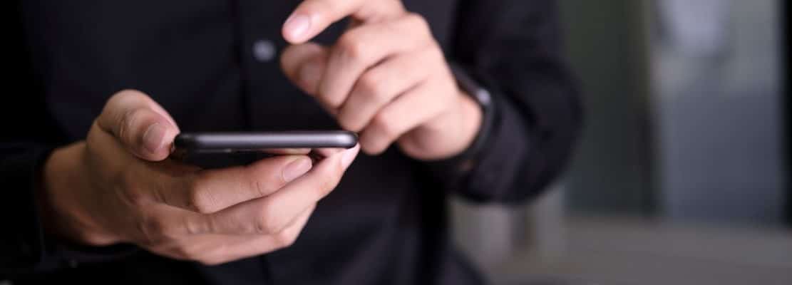 A closeup of a man’s hands using a smartphone