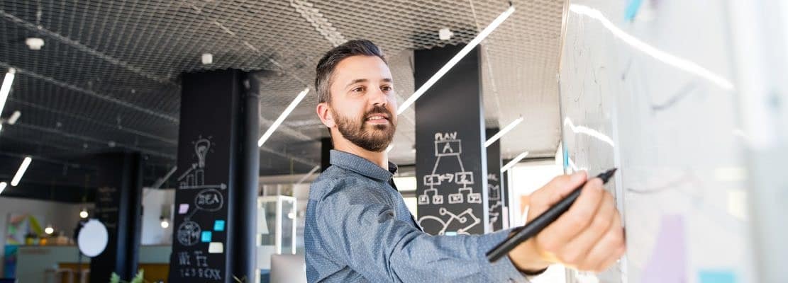 Businessman in the office writing notes on blackboard.