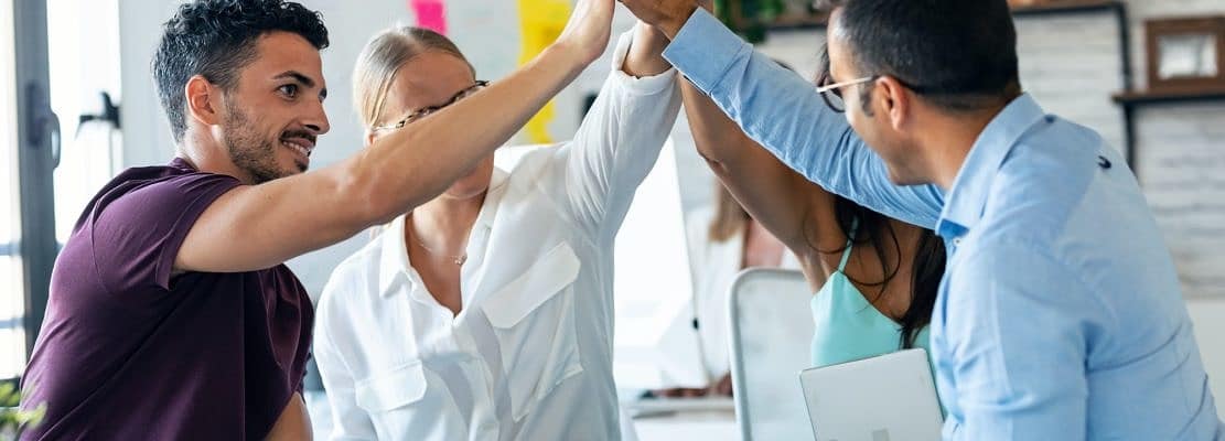 Successful business team celebrating good job while holding up their right hands on coworking place.