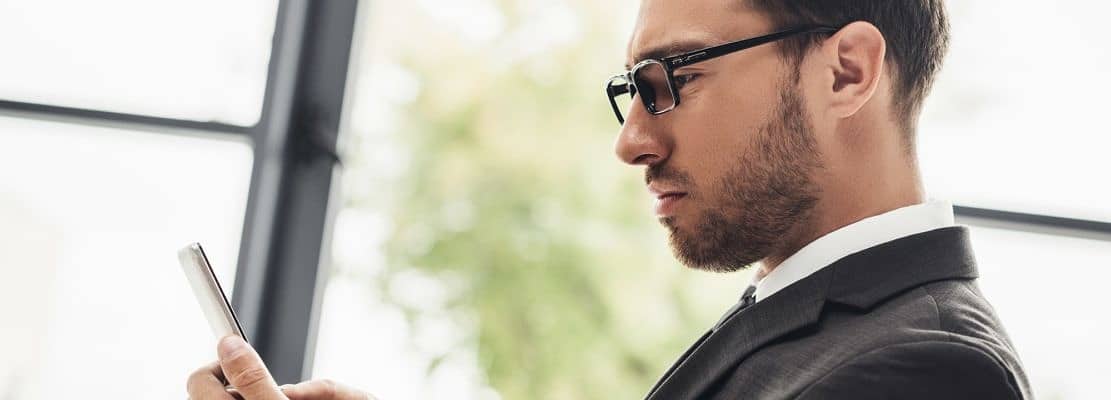 thoughtful young businessman using smartphone