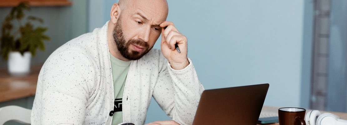 A businessman is thinking about a new project while working at a computer in the kitchen