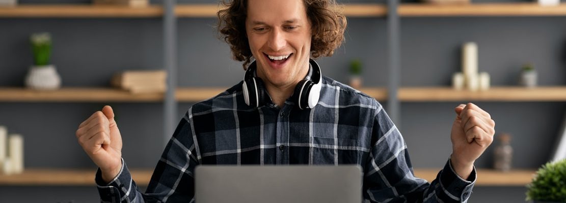Entrepreneur At Laptop Celebrating Business Success Shaking Fists In Office