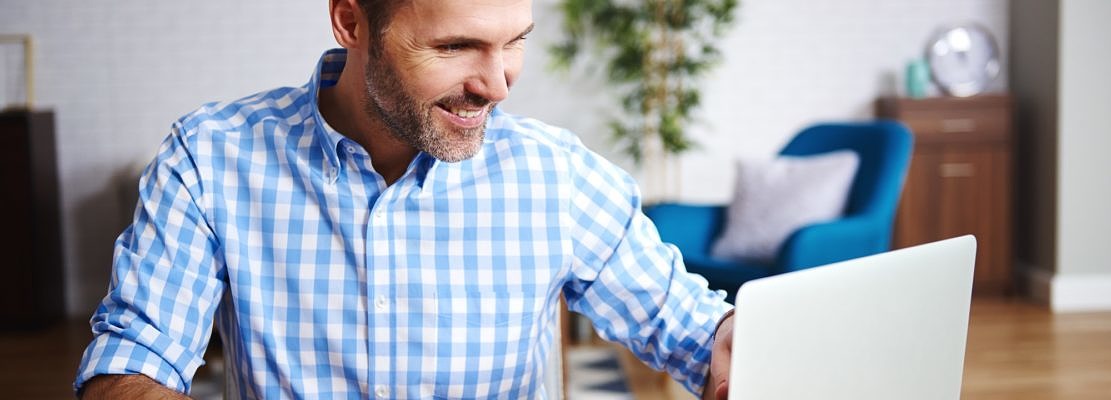 Happy man using laptop in his home office