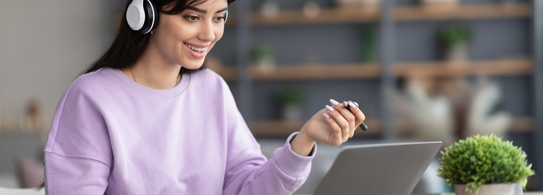 Woman in headphones having video call using laptop and talking