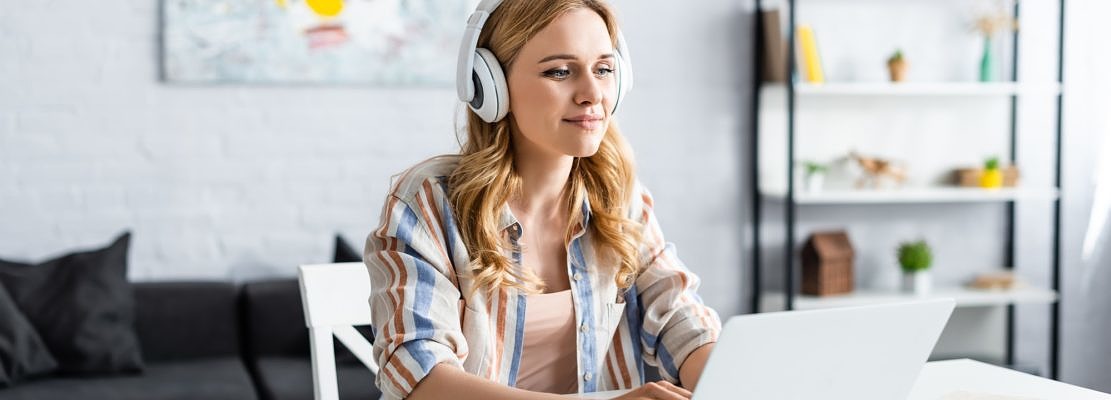 Selective focus of pretty woman working with laptop and headphones