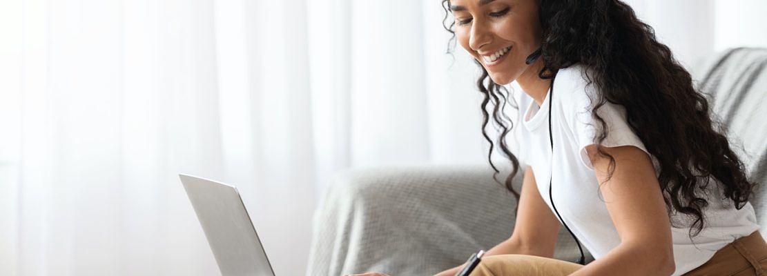 Young lady attending webinar, using laptop and headset
