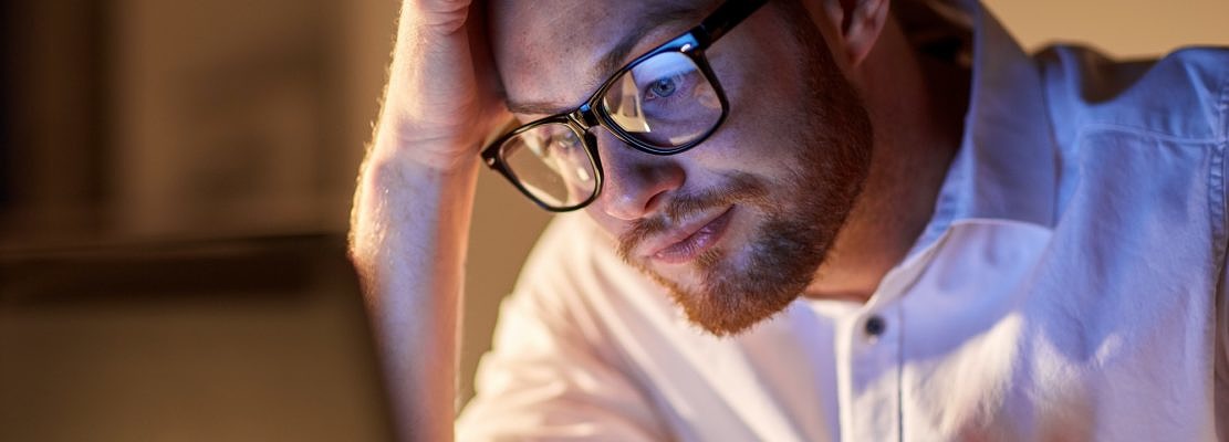 businessman with laptop thinking at night office