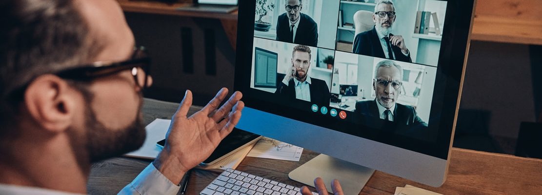 Confident young man having video conference with the colleagues while staying late in the office