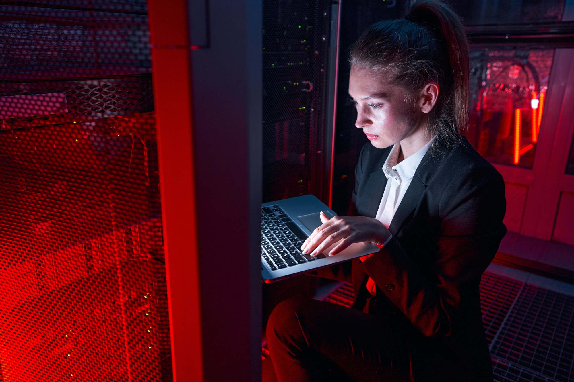 Female technician using laptop to analyze server