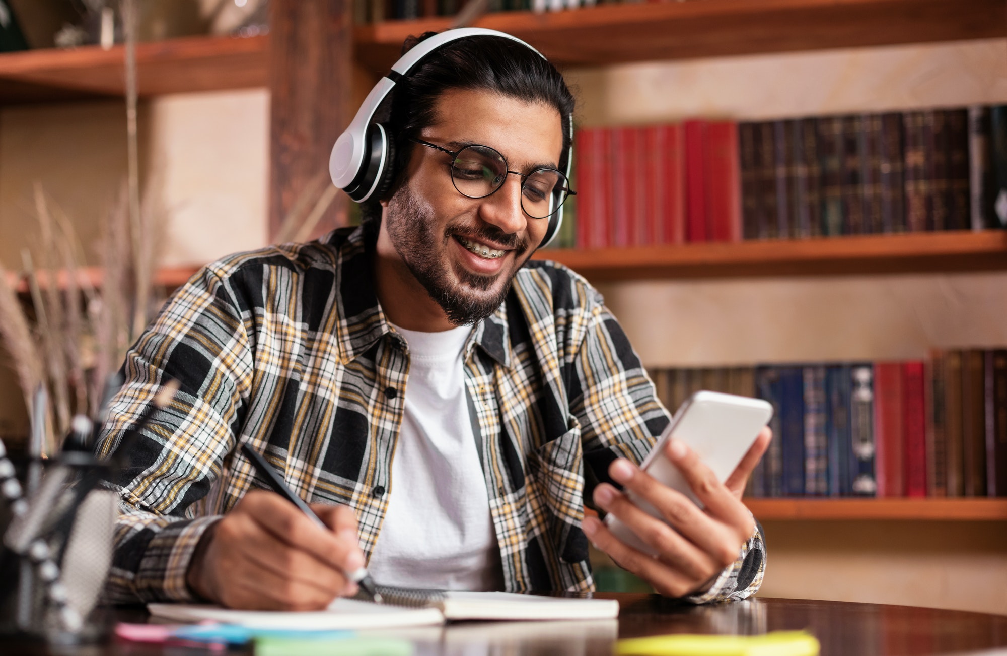 Happy Indian Student With Smartphone Learning Sitting In University Library