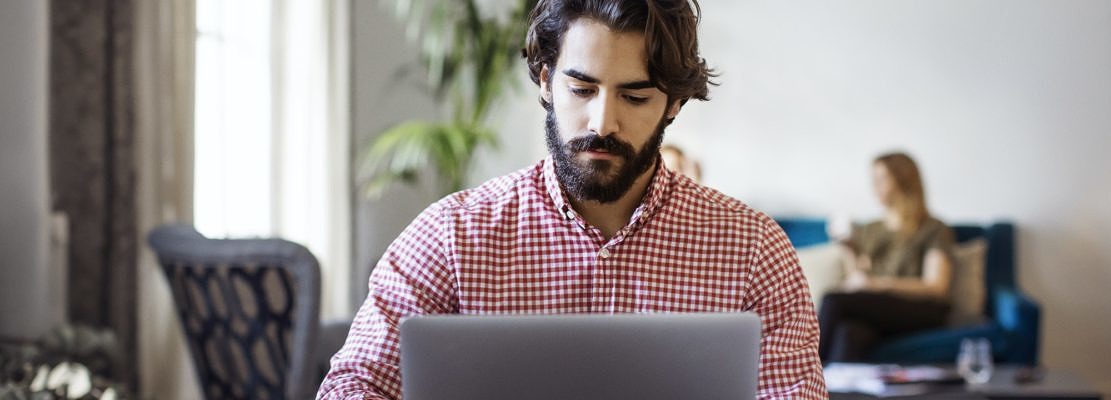 Creative Businessman Working On Laptop While Sitting At Table In Office