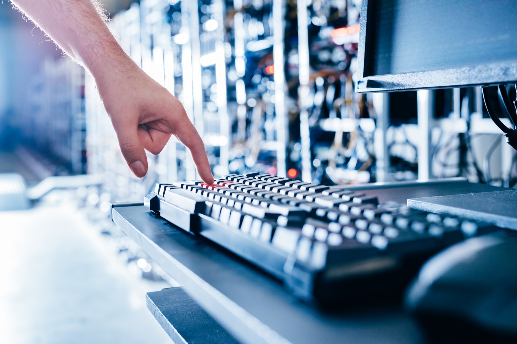 IT specialist pressing red button on keyboard in big data center.