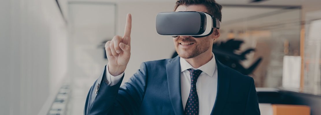 Smiling bearded office employee in suit wearing in VR glasses working in augmented reality in office