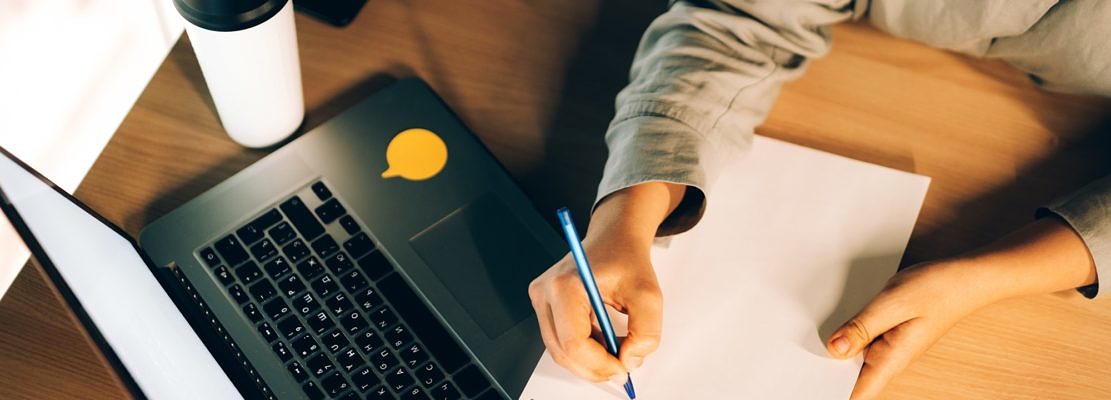 Young woman studying online courses with a laptop, notebook, and coffee