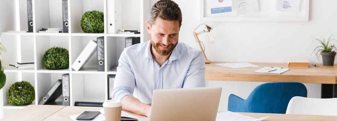 Happy bearded man sitting in office working