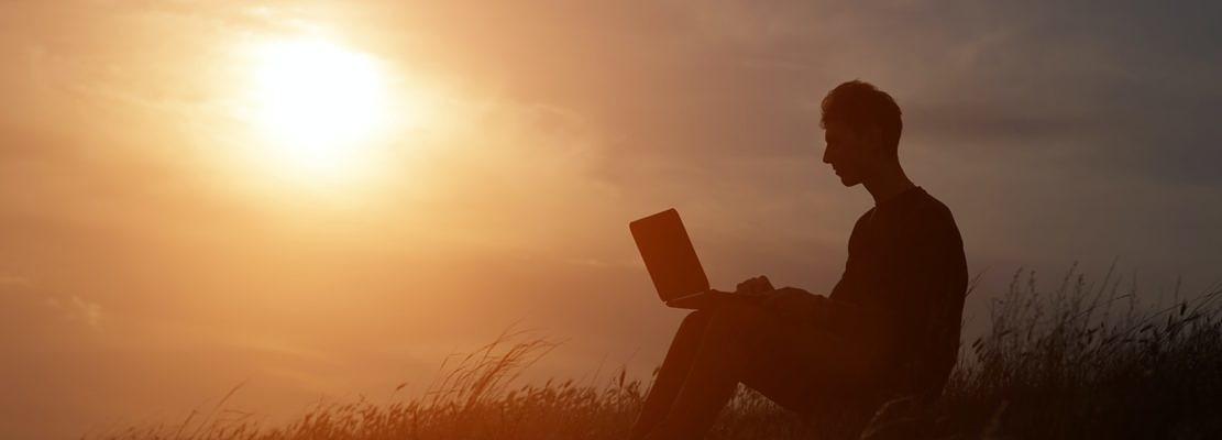 silhouette of happy business man with laptop working on the field