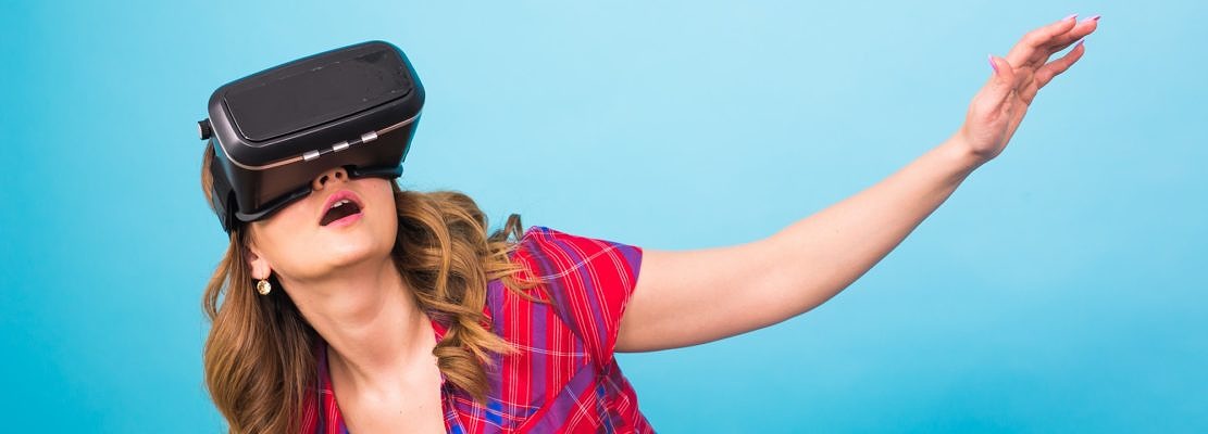 Technology, virtual reality, entertainment and people concept - happy young woman with virtual