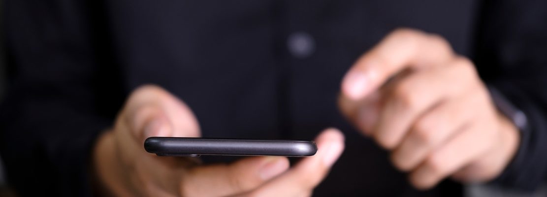 A closeup of a man’s hands using a smartphone