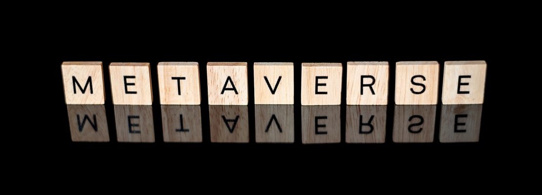 METAVERSE spelled out in wooden letter tiles on shiny black surface with reflection.