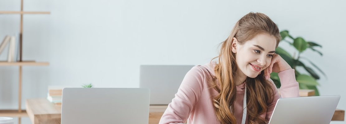 smiling blonde student studying with laptop in computer class