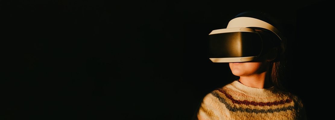 Futuristic shot of a young woman in virtual reality glasses headset enjoying the sunset.