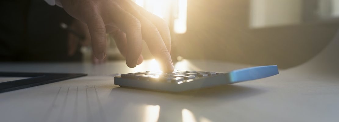 Hand of a businessman using a desk calculator