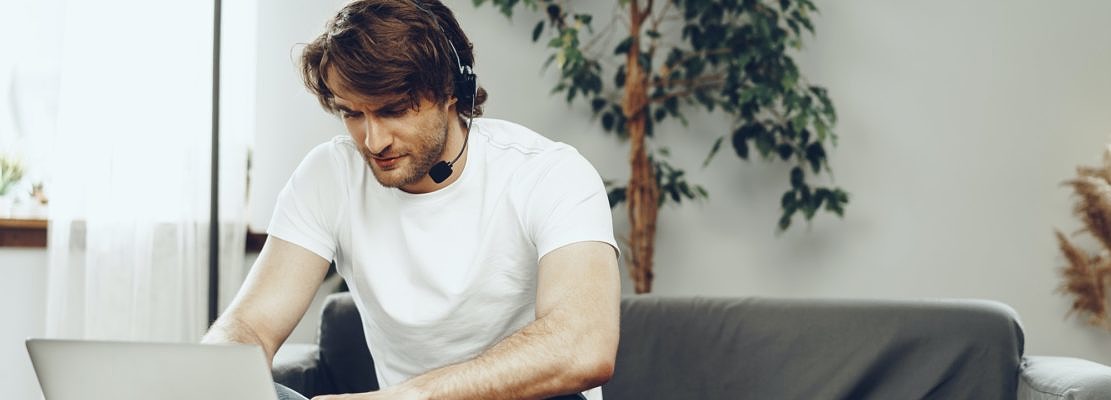 Young man businessman with headset working on laptop from home