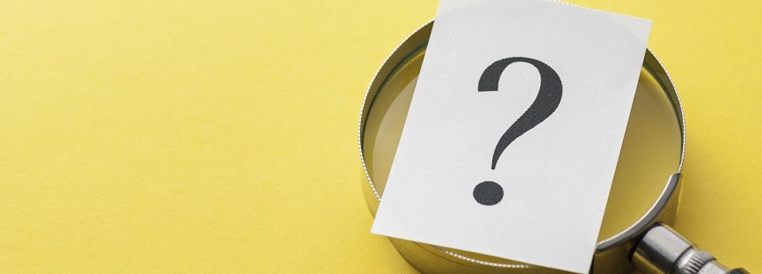 Printed question mark covering a magnifying glass