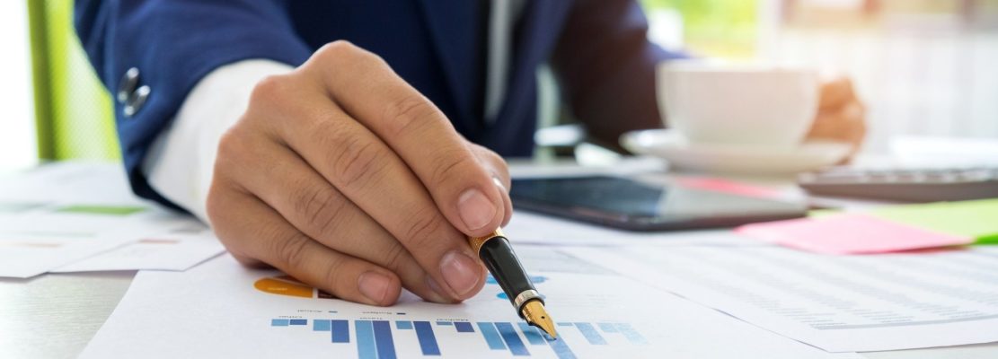 Businessman uses a pen pointing at the chart to analyze the data