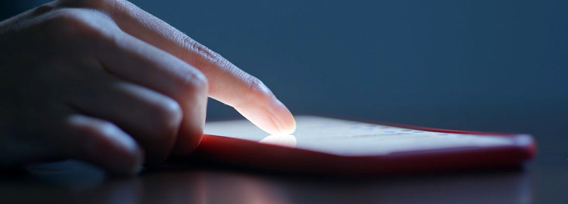 Finger touch on the screen of cellphone at night