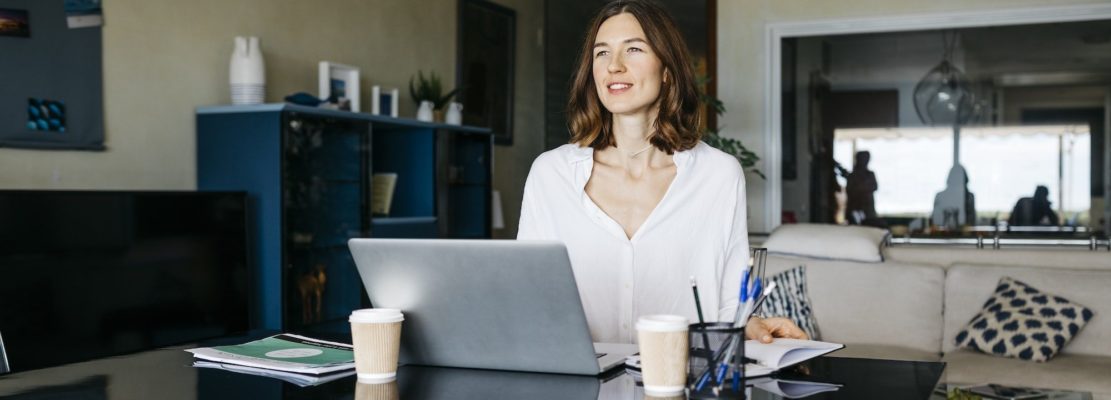 Woman working on table at home with notebook and laptop