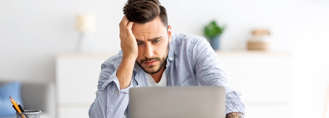Freelance stress. Male freelancer tired after work on laptop at home, having problems with project