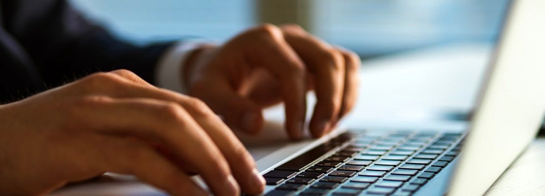 The hands typing on the laptop keyboard