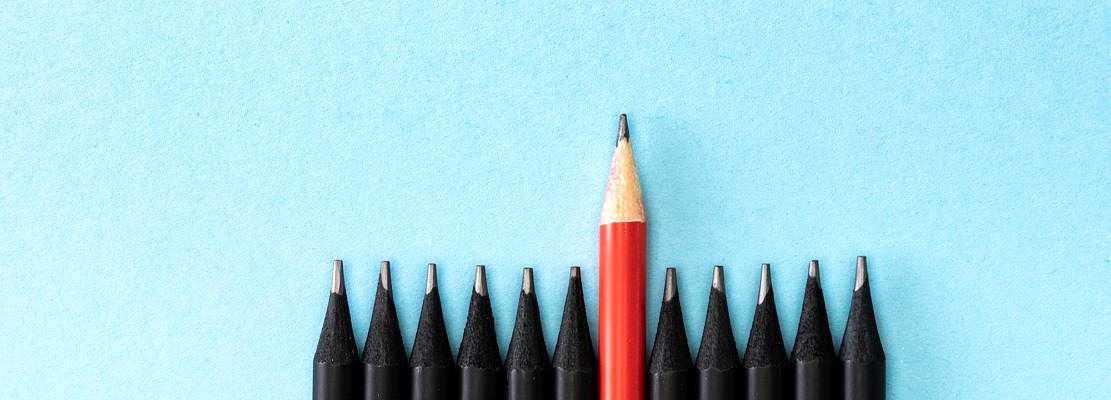 Top view of red pencil among black on blue background