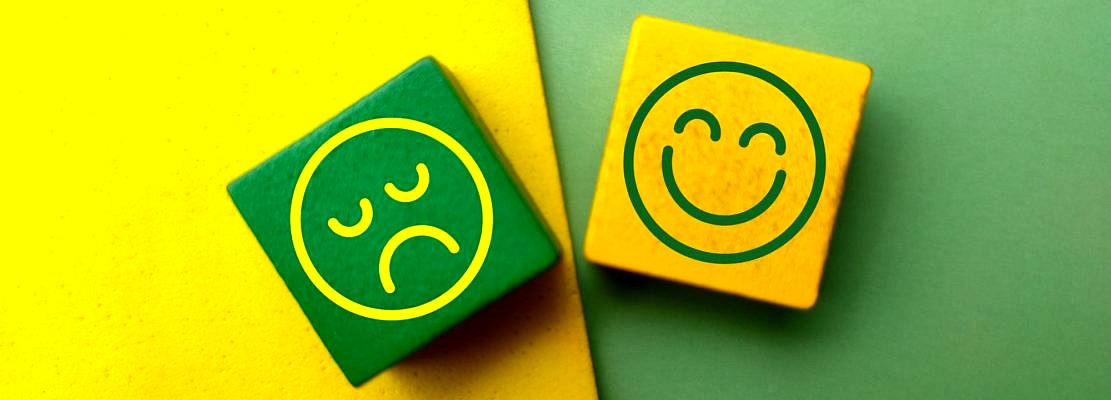 Top view colored wooden cube with the happy and unhappy face icons.