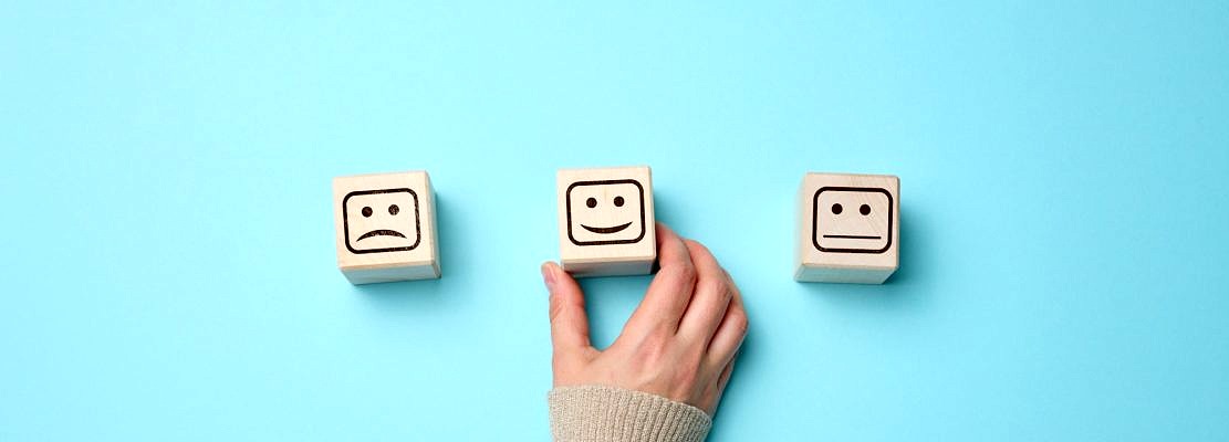 Wooden blocks with different emotions from smile to sadness and a woman's hand