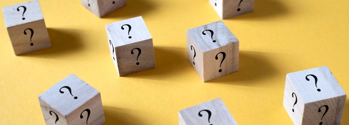 Wooden cube box with question mark on yellow background. Concept of questions, faq and uncertainty