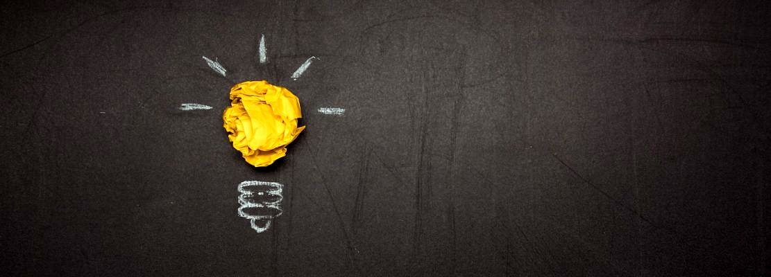 light bulb symbol made of crumpled paper on blackboard